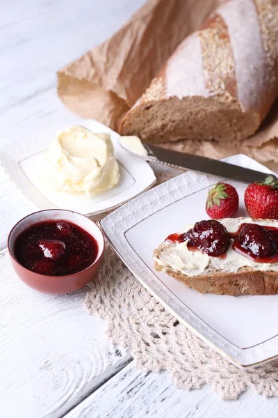 Toast fresco con burro fatto in casa e marmellata di fragole su sfondo di legno chiaro — Foto Stock