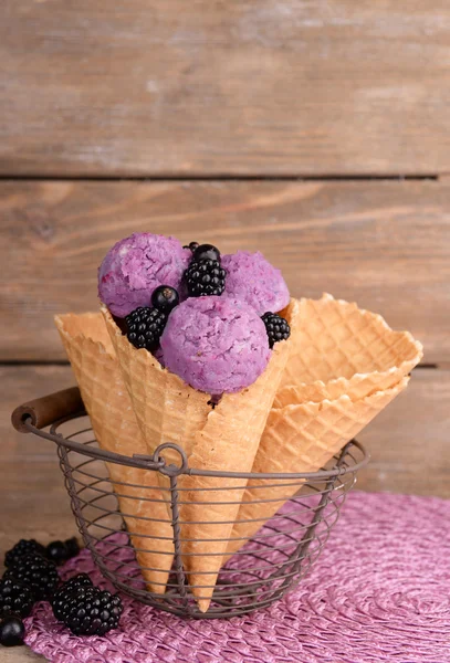 Gelato gustoso con bacche in cono di cialda su fondo di legno marrone — Foto Stock