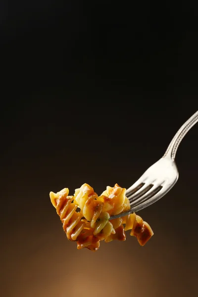 Italiaanse pasta op voorvork op donkere bruine achtergrond — Stockfoto