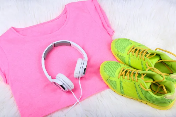 Sportkläder, skor och hörlurar på vita mattan bakgrund. — Stockfoto