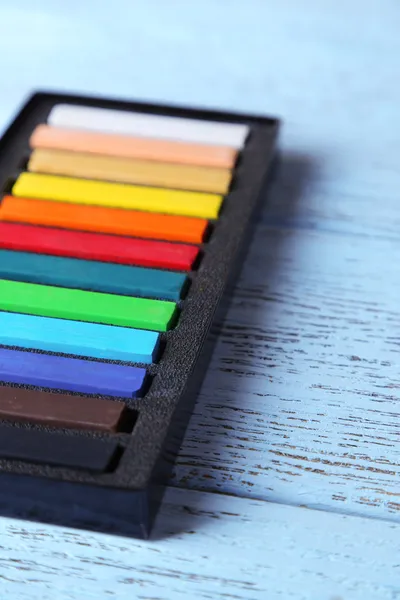 Colorato gesso pastelli in scatola su sfondo di legno — Foto Stock