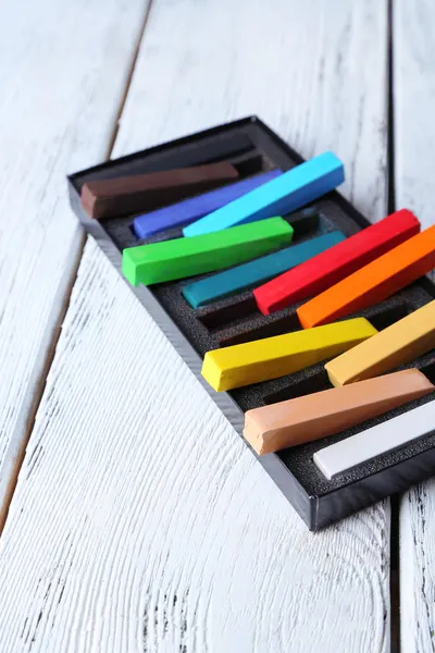 Pasteles de tiza de colores en caja sobre fondo de madera —  Fotos de Stock