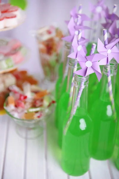 Botellas de bebida con paja y dulces sobre fondo decorativo —  Fotos de Stock