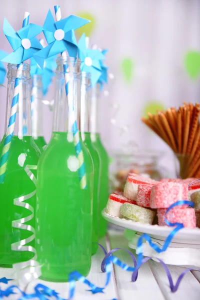 Bottles of drink with straw and sweets on decorative background — Stock Photo, Image