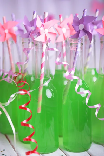 Flaskor av dricka med sugrör på bordet på dekorativa bakgrund — Stockfoto