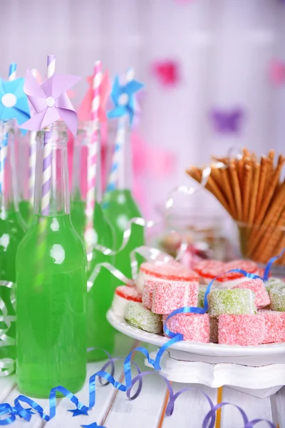 Botellas de bebida con paja y dulces sobre fondo decorativo — Foto de Stock