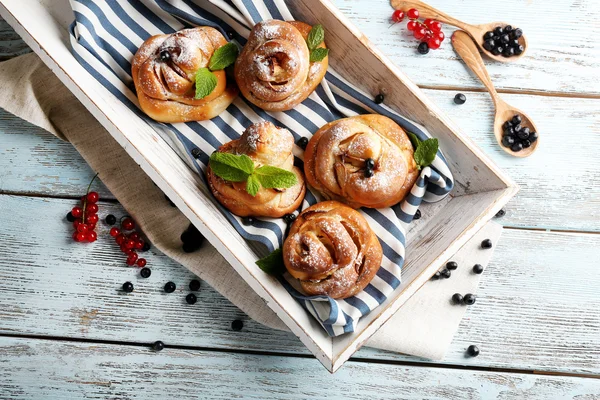 Tasty buns with berries on tray on table close-up — Stock Photo, Image