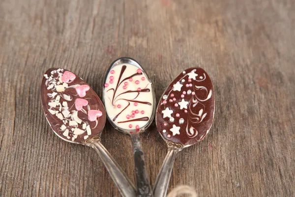 Spoons with tasty chocolate for party on old wooden table — Stock Photo, Image