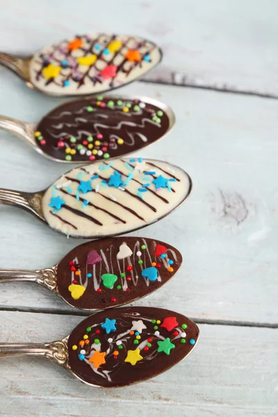 Spoons with tasty chocolate for party on old wooden table — Stock Photo, Image