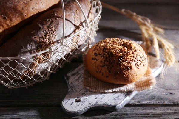 Fresh baked bread in basket, on wooden background — Stock Photo, Image