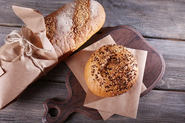 Świeże pieczywo pakowane w papier, na tle drewniane — Zdjęcie stockowe