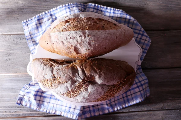 Свежий домашний хлеб, завернутый в бумагу, на салфетке, на цветном деревянном фоне — стоковое фото