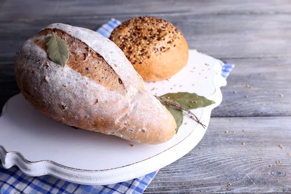 Świeży chleb domowej roboty zawinięte w papier, w serwetkę, na tle drewniane kolor — Zdjęcie stockowe