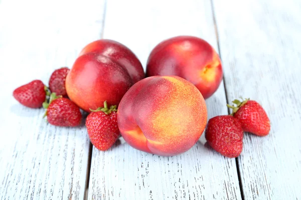 Персики с ягодами на деревянном столе крупным планом — стоковое фото