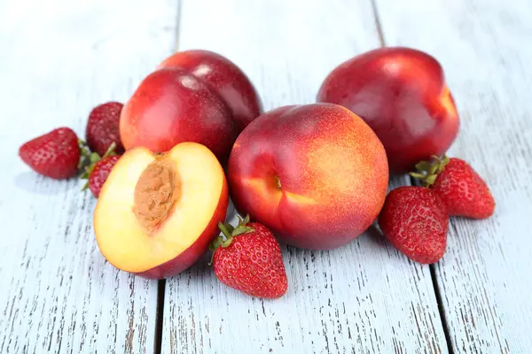 Персики с ягодами на деревянном столе крупным планом — стоковое фото