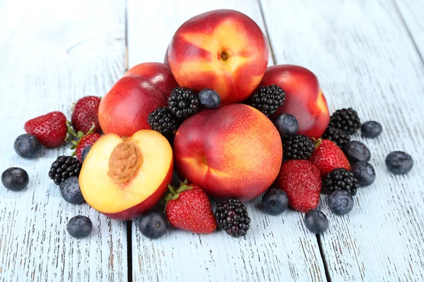 Peaches with berries on wooden table close-up — Stock Photo, Image