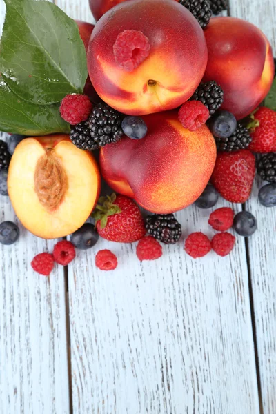 Peaches with berries on wooden table close-up — Stock Photo, Image