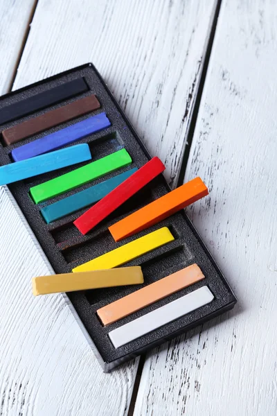 Pasteles de tiza de colores en caja sobre fondo de madera — Foto de Stock