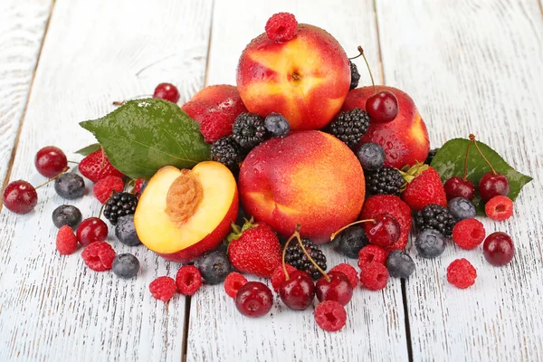 Persik dengan buah beri di meja kayu close-up — Stok Foto