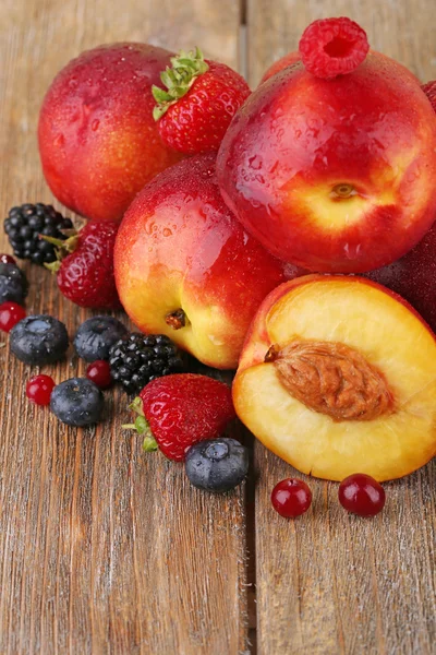 Peaches with berries on wooden table close-up — Stock Photo, Image