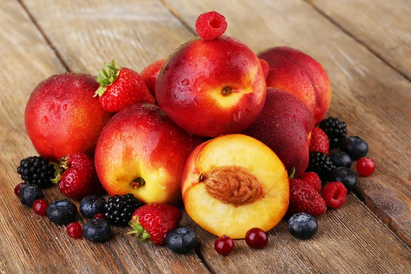 Peaches with berries on wooden table close-up — Stock Photo, Image