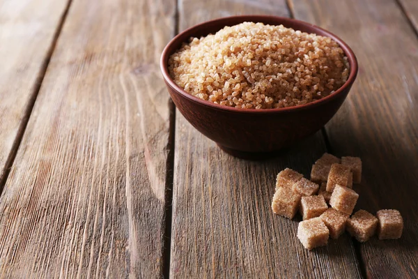 Cubes de sucre brun et sucre cristallin dans un bol sur fond en bois — Photo