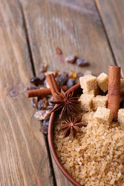 Brown sugar cubes, reed and crystal sugar in bowl on wooden background