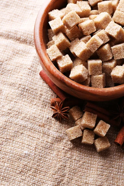 Cuburi de zahăr brun în castron pe fundal sac — Fotografie, imagine de stoc