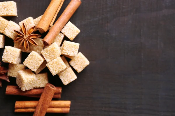 Brown sugar cubes and reed sugar, spices on wooden background — Stock Photo, Image