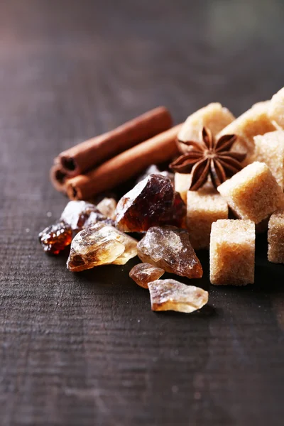 Brown sugar cubes and reed sugar, spices on wooden background — Stock Photo, Image