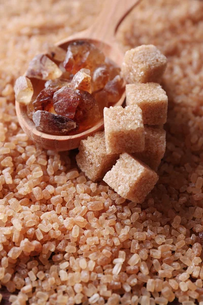 Reed sugar in wooden spoon on brown crystal sugar background — Stock Photo, Image