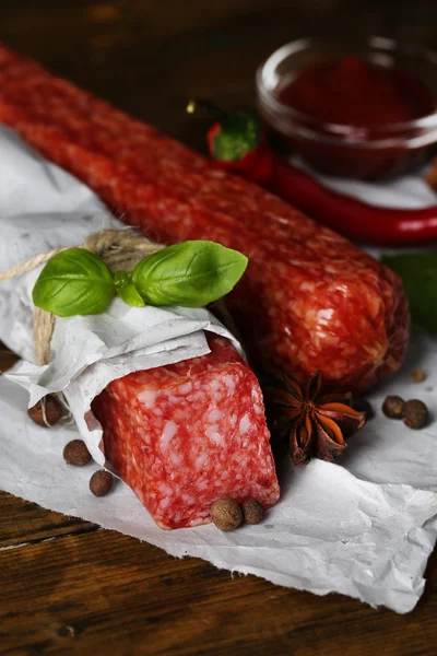 Вкусная колбаса из салями и специи на деревянном фоне — стоковое фото