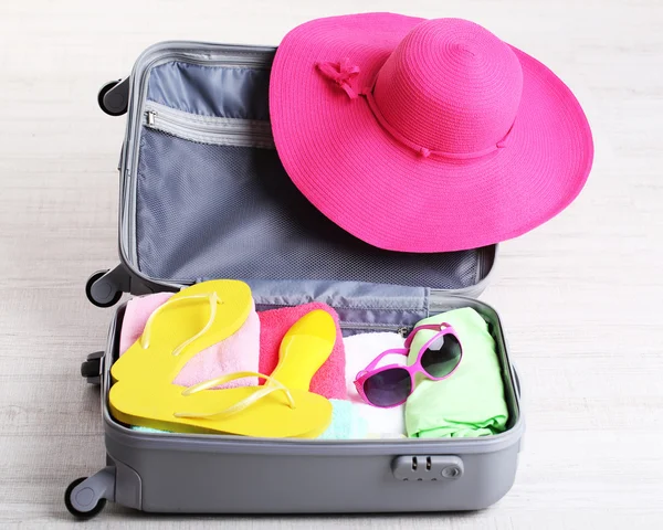 Maleta con cosas en el suelo para viajar cerca del agua para pasar las vacaciones de verano — Foto de Stock