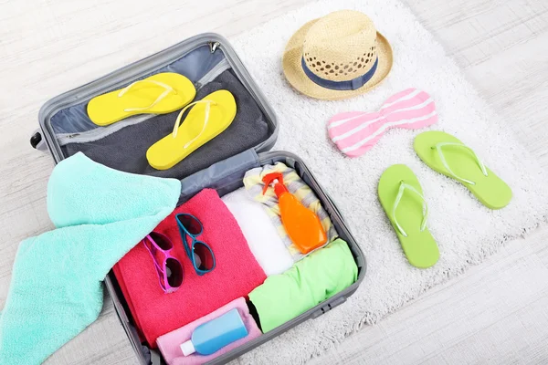 Suitcase with things on white carpet on the floor for travelling somewhere close to water for spending summer vacation — Stock Photo, Image