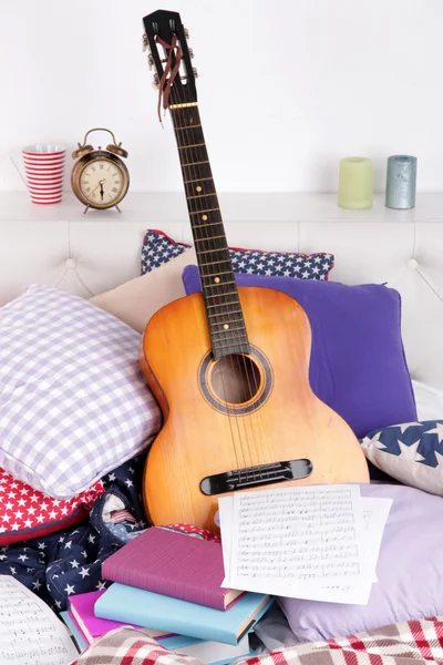 Guitarra em travesseiros em uma cama — Fotografia de Stock