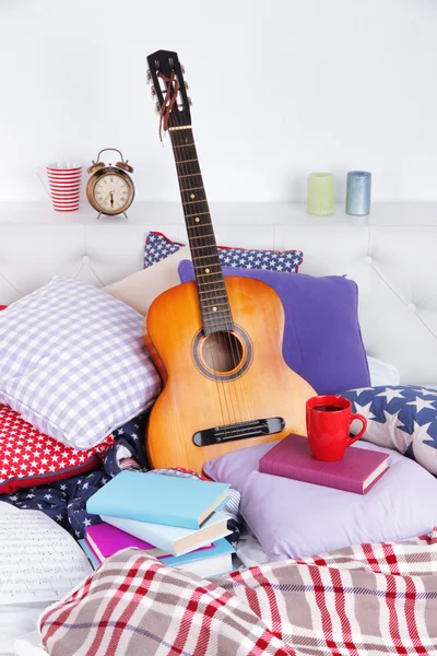 Guitarra sobre almohadas en una cama — Foto de Stock