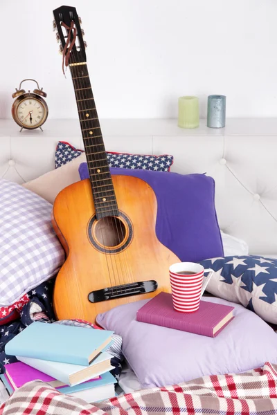 Chitarra su cuscini su un letto — Foto Stock