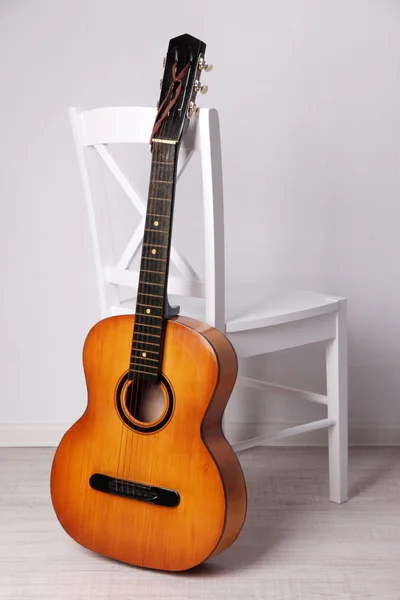 Guitarra em uma cadeira de madeira branca no chão sobre fundo branco — Fotografia de Stock