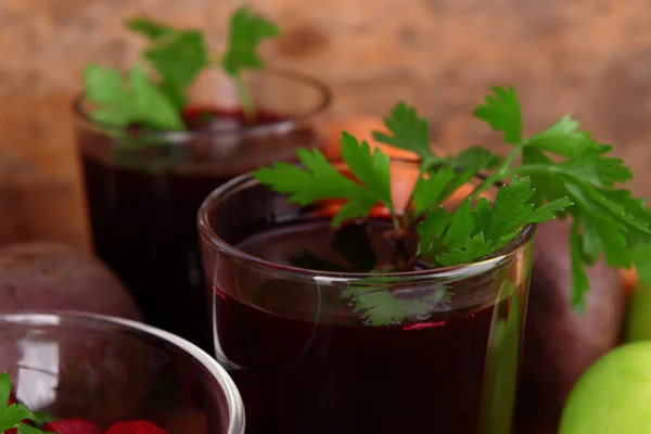 Copos de suco de beterraba fresca e legumes em fundo de madeira — Fotografia de Stock