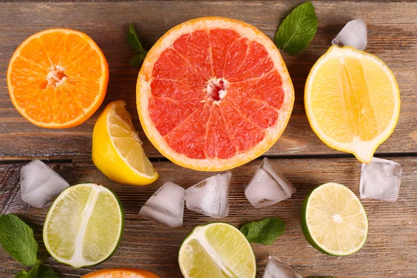 Frutos cítricos suculentos fatiados diferentes com gelo na mesa de madeira — Fotografia de Stock