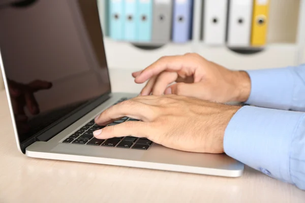 Man aan het werk op laptop op houten tafel op mapachtergrond — Stockfoto