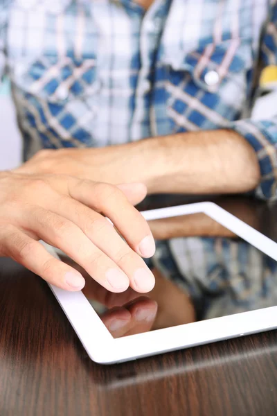 Man sitter på träbord och arbetar på tablett närbild — Stockfoto