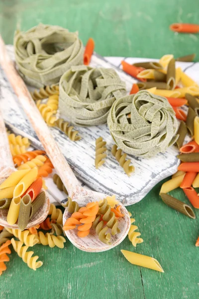Kleurrijke pasta in houten lepels op houten achtergrond — Stockfoto