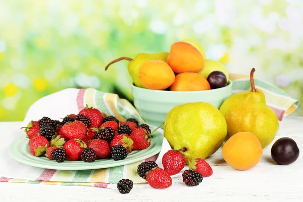 Frutas maduras e bagas na mesa em fundo brilhante — Fotografia de Stock