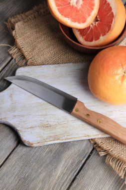 Olgun greyfurt ve ahşap zemin üzerinde kesme tahtası üzerinde bıçak