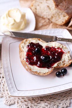 taze ekmek ile ev yapımı tereyağı ve blackcurrant jam hafif ahşap zemin üzerinde plaka üzerinde