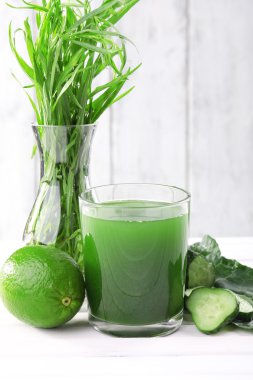 bardak taze limon suyu, limon, salatalık dilimleri ve çim ahşap duvar önündeki masanın üzerine vazo