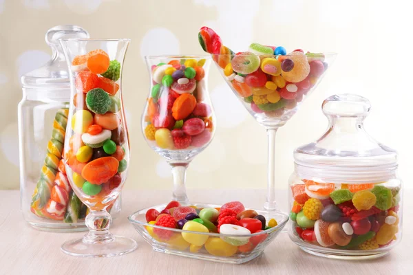 Verschiedene bunte Fruchtbonbons in Gläsern auf Tisch auf hellem Hintergrund — Stockfoto