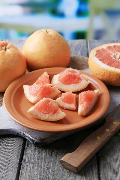 Ripe grapefruits and knife on cutting board, on wooden background — Stock Photo, Image