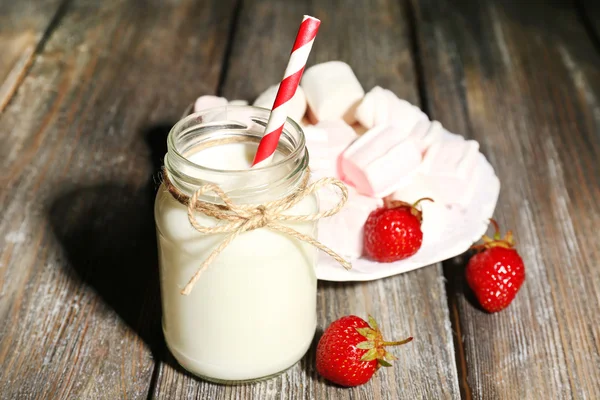 Melk in flessen met papier rietjes op tafel — Stockfoto